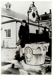 Girl seated on wishing well, 1940s